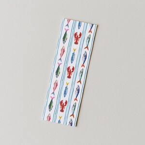 May include: A rectangular bookmark featuring a white background with vertical light blue stripes. The design includes a repeating pattern of small, colorful illustrations of various fish and red lobsters arranged in columns between the stripes.