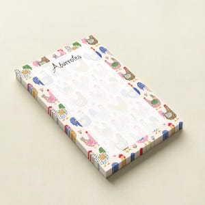 May include: A rectangular notepad with a white background and a repeating pattern of colorful chickens. The border features a decorative design of chickens and floral elements. The word "Abarrotes" is handwritten on the top.
