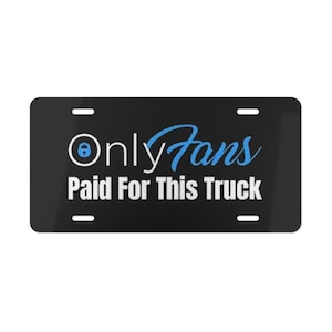 May include: Black license plate with the text "OnlyFans Paid For This Truck" in white and blue. The OnlyFans logo is in the upper left corner. The plate has four mounting holes.