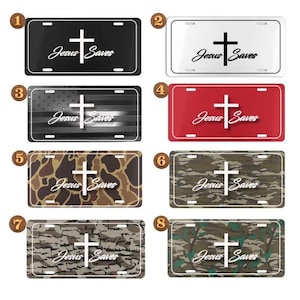 May include: Collection of license plates with the text "Jesus Saves" and a cross design. The plates feature various backgrounds, including black, white, red, camouflage, and an American flag design. The text is in a cursive font.