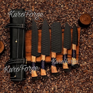 May include: A set of six black kitchen knives with wooden handles and a black leather knife roll. The blades have a textured surface. The knife handles have a blue and purple accent.