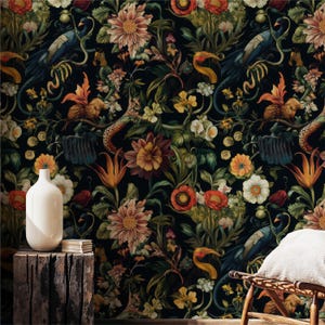 May include: Dark floral wallpaper featuring a dense pattern of flowers, birds, and snakes in shades of orange, yellow, and blue against a black background. A white vase sits on a wooden block in the foreground. The overall theme is botanical and vintage.