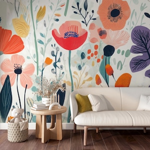 May include: A colorful floral wallpaper featuring large, stylized flowers in shades of red, orange, pink, and purple against a light background. A white sofa with yellow and white pillows sits in front of the wallpaper. A small wooden table and a basket with a teddy bear are also visible.