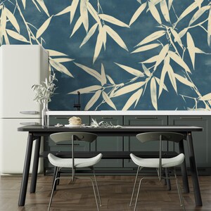 May include: A modern kitchen with a dark blue wall featuring a cream-colored bamboo leaf pattern. The room includes a black table, two chairs, a white refrigerator, and dark green cabinets. The floor is made of wood.