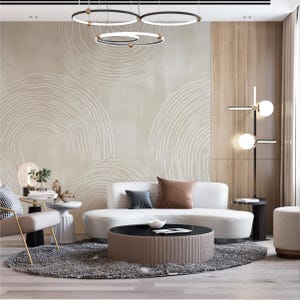 May include: A modern living room with a neutral color palette. Features a white sofa, round coffee table, and a gray rug. The walls are adorned with abstract art and wood paneling. A stylish light fixture hangs from the ceiling.