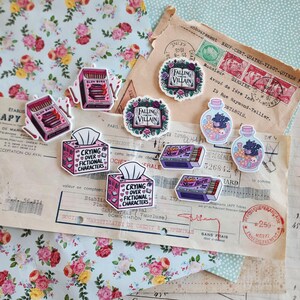 May include: A collection of decorative stickers featuring various designs including matchboxes labeled Slow Burn, tissue boxes labeled Crying Over Fictional Characters, books titled Falling for the Villain, and glass bottles containing small creatures.