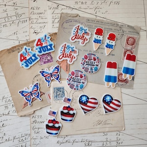 Può includere: Una collezione di adesivi e abbellimenti a tema patriottico. I disegni includono il testo "4th of July", bandiere americane, farfalle, coni gelato, ghiaccioli, cupcake e forme di cuore. La tavolozza dei colori presenta rosso, bianco e blu.