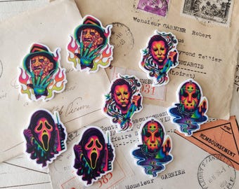 Puede incluir: Una colección de ocho pegatinas troqueladas con ilustraciones coloridas en tonos neón de personajes de películas de terror, incluyendo figuras con sombreros y guantes de garras, personas enmascaradas con cuchillos y personajes encapuchados con teléfonos.