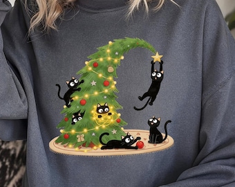 Op de afbeelding: Donkergrijze sweatshirt met een grillig kerstboomontwerp en zwarte katten. De boom is versierd met lichtjes en ornamenten, en verschillende katten spelen ermee. Een ster staat bovenop de boom.