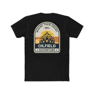 May include: Black t-shirt with a graphic that reads "MAKING THEM SQUIRT - 1894 - OILFIELD ADVENTURE." The design features a sun, oil derricks, and a desert scene in yellow, orange, and blue.