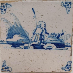 May include: Square ceramic tile with a hand-painted design in shades of blue on a white background. The image depicts a figure with a staff riding a stylized sea creature. Decorative floral motifs are in each corner. The tile has a slightly aged appearance.