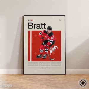 May include: A framed poster featuring a hockey player in a red and black uniform, holding a hockey stick. The poster has the name "Bratt" in large letters, the number "67", and a signature. The background is a mix of red and beige.