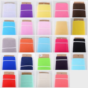 May include: A variety of colors of tulle fabric rolls, each wrapped in brown paper with a white label. The colors include white, purple, yellow, pink, brown, light blue, light pink, beige, yellow, gray, orange, blue, red, black, green, navy blue, lime green, ivory, and peach.