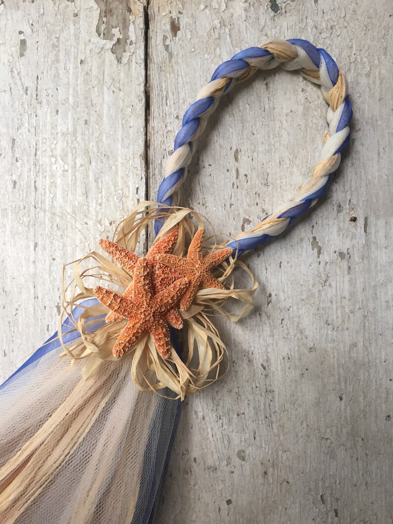 May include: A blue and white braided rope with a starfish decoration. The rope is tied into a loop and the starfish is attached to the rope with a brown ribbon.