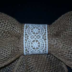 May include: A brown burlap bow with a white lace trim. The bow is tied in the center with a white lace ribbon.