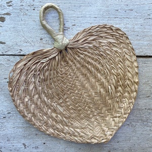 May include: A woven, light brown, heart-shaped fan with a white handle.