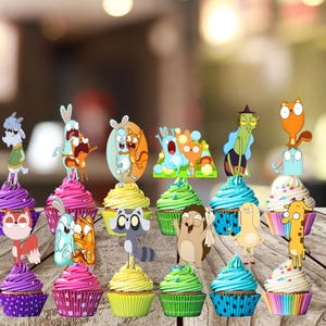 Op de afbeelding: Een verzameling van twaalf cupcakes in kleurrijke papieren vormpjes, elk voorzien van een unieke cartoonfiguur als decoratie. De figuren tonen verschillende dieren zoals een geit, een eekhoorn, een wasbeer, een giraffe en een egel.