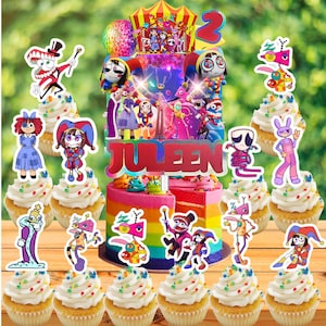 May include: A colorful birthday cake with a rainbow design, topped with cartoon character decorations and the name "Juleen". Cupcakes with character toppers surround the cake. The number "2" is also on the cake.