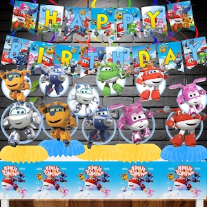 May include: A Super Wings themed party decoration set featuring a Happy Birthday banner with cartoon airplane characters, multiple circular cutouts of various robot planes, and a blue table skirt with the Super Wings logo and characters.