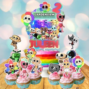 May include: A birthday cake with rainbow frosting, topped with a colorful cake topper featuring cartoon characters and the name "Juleen". Cupcakes with pink frosting and character toppers are arranged around the cake. The number "2" is also on the cake.