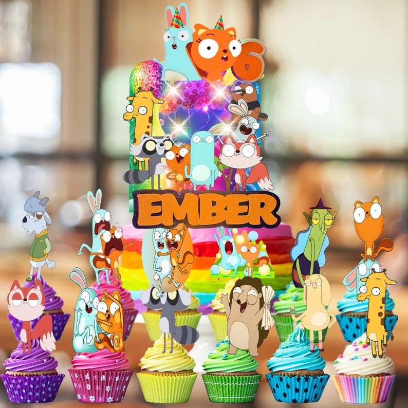 Op de afbeelding: Een taarttopper met de naam EMBER in oranje letters, omringd door kleurrijke stripfiguren en een cijfer 6, geplaatst boven een set cupcakes met verschillende kleuren glazuur en bijpassende stripfiguur-toppers.