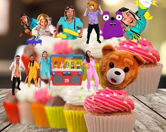 Puede incluir: Una colección de adornos para cupcakes con temática de Danny Go que incluye varios personajes, un radiocasete rojo con el texto Danny Go y una cabeza de oso pardo, dispuestos sobre cupcakes con glaseado rosa y blanco en moldes de papel.