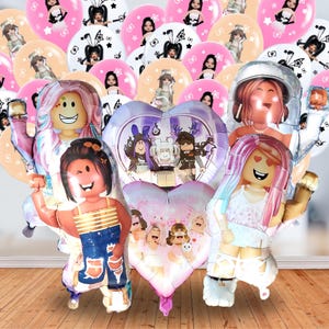 May include: A collection of foil balloons featuring various Roblox-style character designs. The set includes multiple round balloons with individual character prints and two heart-shaped balloons displaying groups of characters in pink and purple tones.