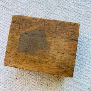 Puede incluir: Una caja de madera rectangular con un acabado marr&oacute;n desgastado. La caja tiene una peque&ntilde;a mancha gris en la parte superior.