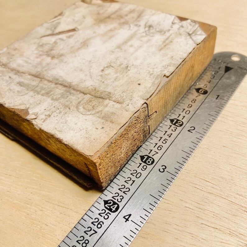 May include: A close-up of a wooden block with a white surface and a ruler measuring 45.7 cm. The block has a rough texture and appears to be old.