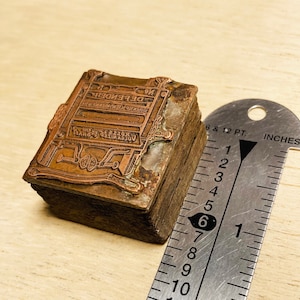 May include: A vintage copper printing block with the text "VOLCANIZED RUBBER & BELTING THE "NO" DEFENDER"  GOOD FOR ALL KINDS OF MACHINERY"  The block is approximately 2 inches wide and 2 inches tall.