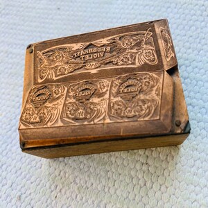 Puede incluir: Un bloque de impresi&oacute;n de madera vintage con las palabras "VIOLET REDBREAST" y "VIOLET" en relieve. El bloque tiene un dise&ntilde;o decorativo con motivos florales.
