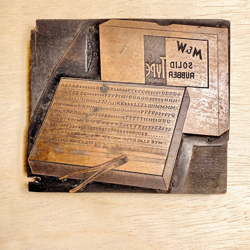 May include: A vintage wood printing block with a metal typeface set. The block is labelled "Rubber Solid Type" and "W.J.M.". The typeface includes the alphabet, numbers, and punctuation marks.