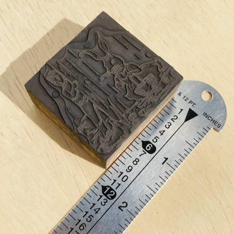 Pu&ograve; includere: Un blocco di stampa in legno con un disegno intagliato di un coniglio e una persona. Il blocco &egrave; largo circa 5 cm.