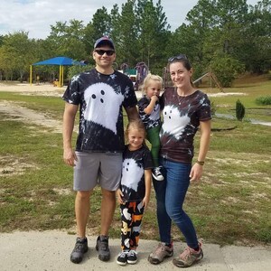 Peut inclure: Un ensemble de t-shirts assortis en tie-dye noir et blanc arborant un grand motif de fant&ocirc;me blanc avec deux yeux noirs. Les t-shirts sont port&eacute;s par un groupe de quatre personnes, dont un enfant en leggings &agrave; motifs et un autre en pantalon vert.