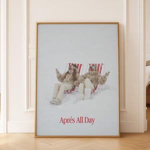 Pode incluir: Uma impressão emoldurada com duas figuras relaxando em cadeiras listradas em vermelho e branco em um cenário de neve. Eles estão usando roupas de inverno. O texto "Après All Day" é exibido em vermelho na parte inferior da impressão.