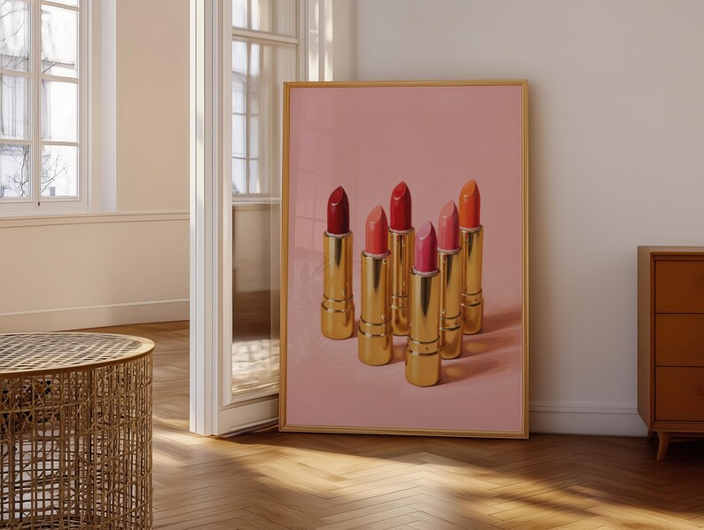 Digital art print of classic gold lipsticks in various pink and red hues, displayed in a wooden frame leaning near a softly lit window — feminine retro wall decor.