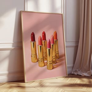 Retro makeup print with gold lipsticks in warm red and pink tones — vintage-inspired digital poster with soft shadows on a pastel pink background.