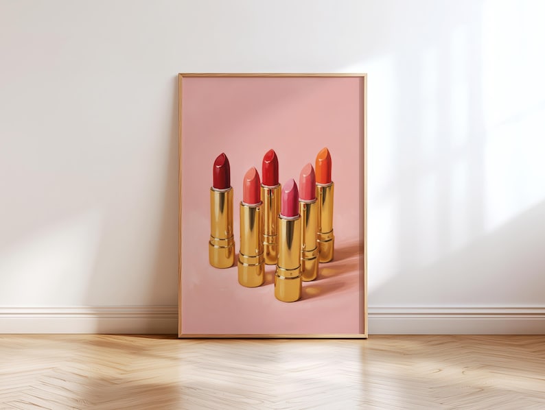 Printable wall art featuring six gold lipsticks in shades of red, coral, and pink on a soft pink background — elegant retro makeup illustration for vanity or dressing room decor.