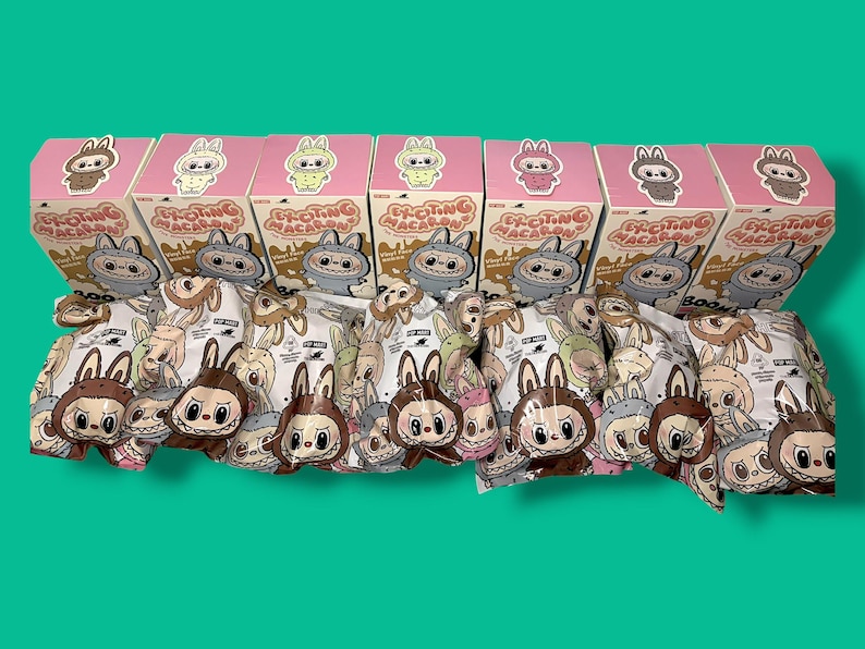K&ouml;nnte beinhalten: Eine Sammlung von Sammler-Vinylfiguren und -Boxen. Die rosa Boxen zeigen Illustrationen von Hasenfiguren. Die Figuren befinden sich in einer transparenten Verpackung mit verschiedenen Designs zum Thema Hase. Der Text "EXCITING MACARON" ist auf den Boxen zu sehen.