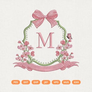 May include: Embroidered design featuring a pink bow, the letter "M", and floral accents. A pink banner is at the bottom, and a butterfly is on the right. The design is framed by a green border with small dots.