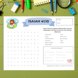 May include: A white word search activity sheet titled Isaiah 41:10 featuring a cartoon illustration of a person reading a book on a green patch, a grid of letters, a list of words to find, a hidden message section, and a small pink heart with a cross.