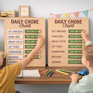 Könnte beinhalten: Zwei tägliche Aufgaben-Tafeln aus Holz mit dem Text "Daily Chore Chart". Die Tafeln haben eine Liste von Aufgaben mit "You Did It!"-Knöpfen. Ein Junge und ein Mädchen interagieren mit den Tafeln. Ein Teddybär und ein Spielzeugauto stehen auf einem Regal.