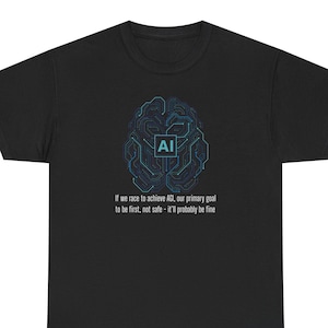 Op de afbeelding: Zwart T-shirt met een blauw hersenvormig printontwerp van een printplaat en de letters "AI". De tekst eronder luidt: "Als we ons haasten om AGI te bereiken, is ons belangrijkste doel om als eerste te zijn, niet veilig - het komt waarschijnlijk goed."