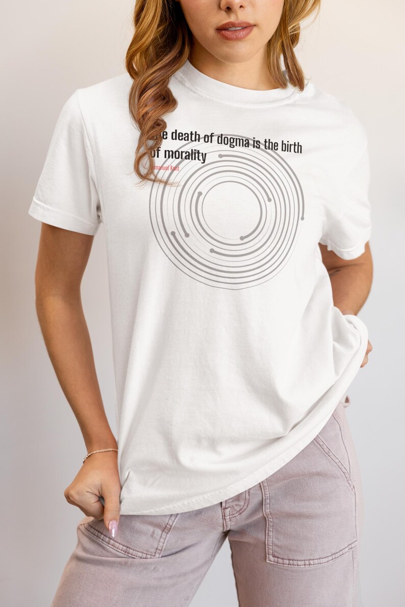 May include: White t-shirt with the text "The death of dogma is the birth of morality" and a gray circular design. The shirt is a short-sleeved, casual style.