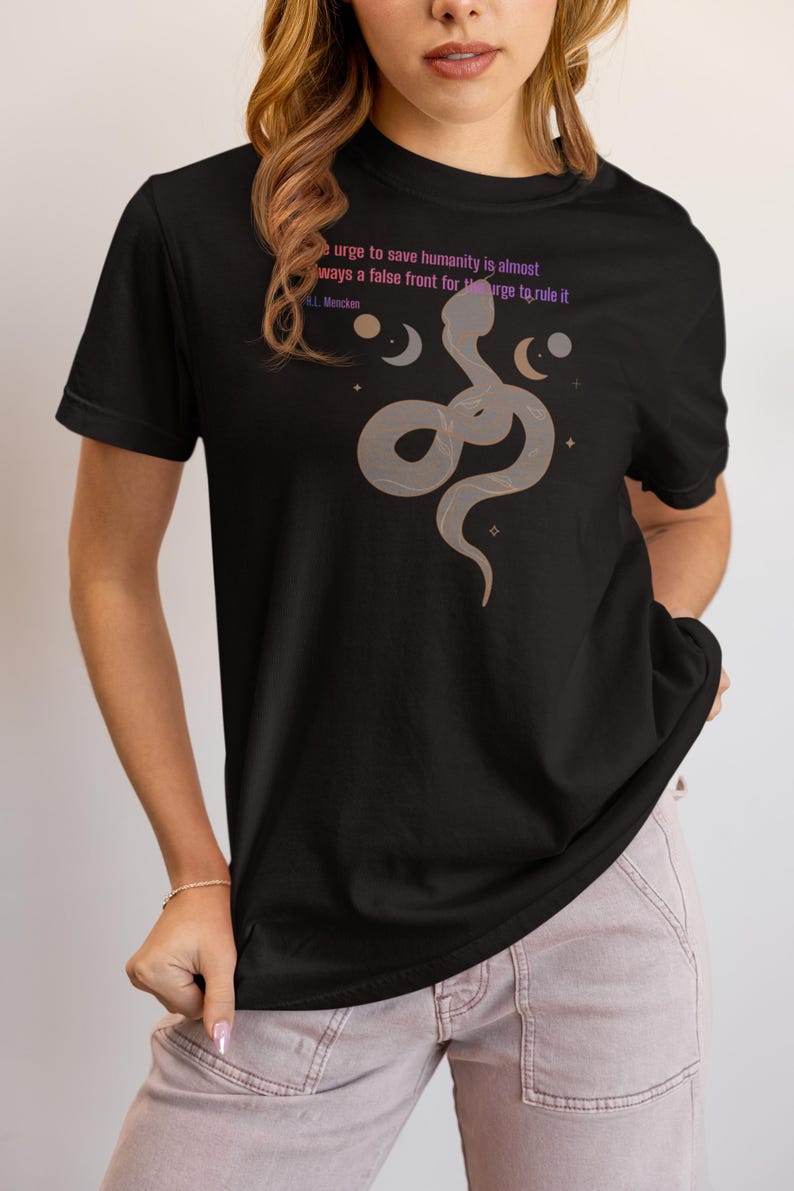 May include: Black t-shirt featuring a stylized snake design with moons and stars. The shirt includes the quote "urge to save humanity is almost always a false front for the urge to rule it" by H.L. Mencken.