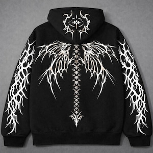 Könnte beinhalten: Ein schwarzer Kapuzenpullover mit einem weißen Grafikdruck, der eine stilisierte Wirbelsäule und flügelartige Strukturen auf dem Rücken zeigt. Die Kapuze ist mit einem kreisförmigen Emblem versehen und beide Ärmel tragen weiße Tribal-Muster.