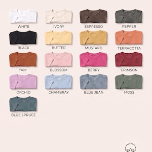 May include: A color palette chart for Comfort Colors 1717 t-shirts, displaying seventeen folded shirts in various shades including white, ivory, espresso, pepper, black, butter, mustard, terracotta, yam, blossom, berry, crimson, orchid, chambray, blue jean, moss, and blue spruce.