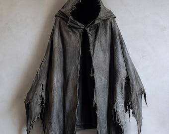 May include: A dark gray hooded cloak featuring a distressed, tattered hemline and a pointed hood. The fabric has a weathered, textured appearance with frayed edges along the bottom and sides, creating a layered, uneven silhouette throughout.