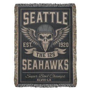 Könnte beinhalten: Eine schwarze gewebte Decke mit dem Wort "SEATTLE" oben und einem Schädel mit Helm und Flügeln in der Mitte. Unter dem Schädel steht der Text "THE 12S" und "SEAHAWKS". Unten steht "Super Bowl Champs" und "XLVIII-LX".