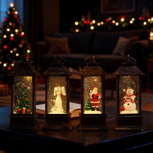May include: Four antique-style Christmas snow globe lanterns. Each lantern features a different holiday scene: a Christmas tree, an angel, Santa Claus, and a snowman. The lanterns are on a dark surface with a Christmas tree and lights in the background.